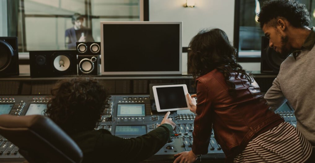 sound producers using tablet together at recording studio